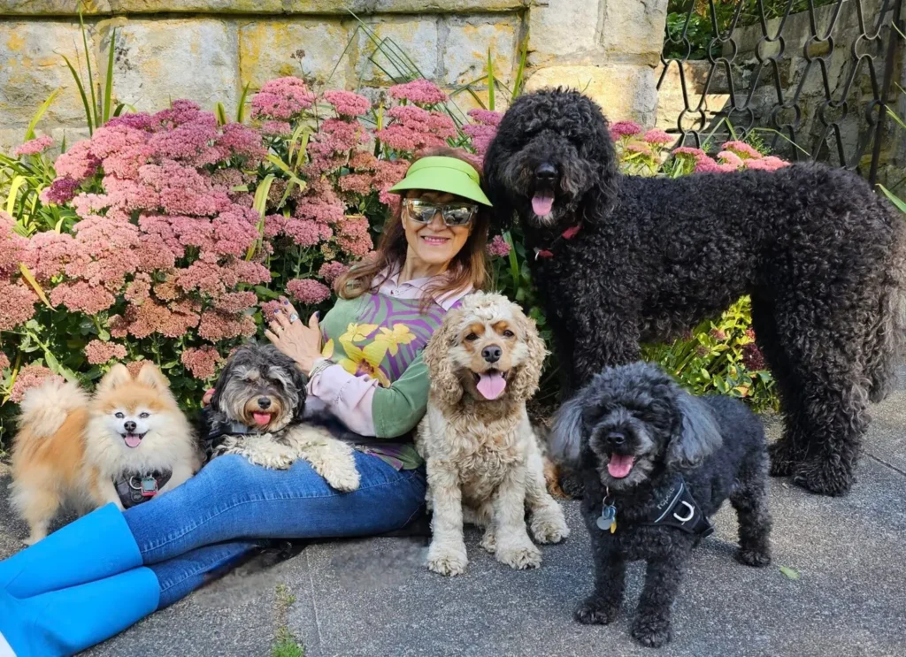 Yvonne sitting on the ground with a group of dogs in a garden setting