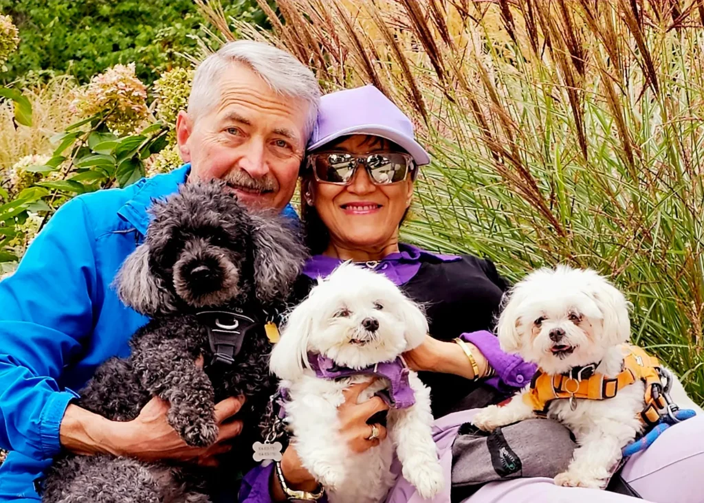 Yvonne and Ken Gardner smiling while holding dogs outdoors