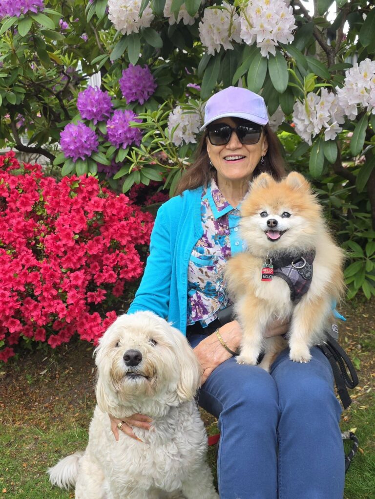 Yvonne outdoors with a Pomeranian and a white dog.